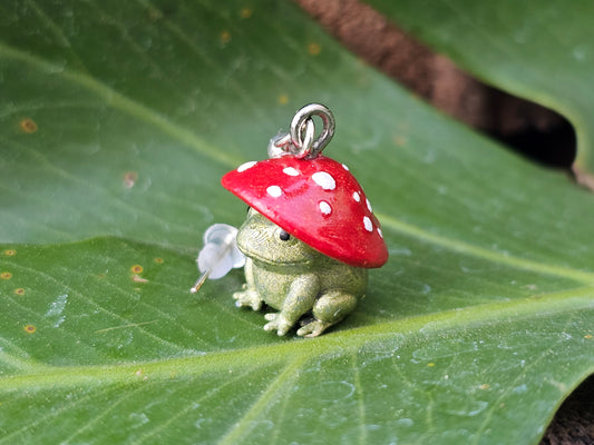 Red mushroom frog earring on a green leaf